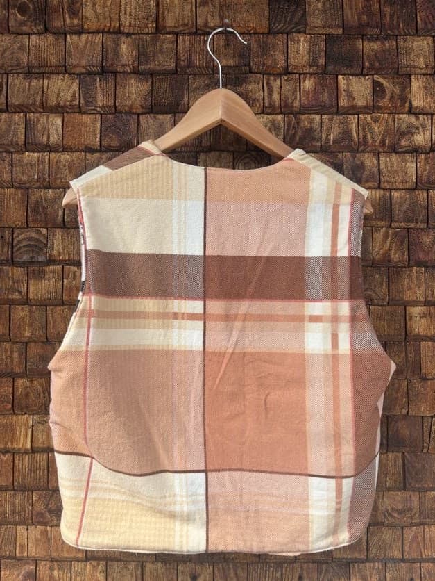 Rückansicht der gewendeten Frottee-Weste 'Clementine' von Old Wave. Zeigt das gemusterte Karo-Design in warmen Erdtönen auf der Rückseite vor einer Backsteinwand.