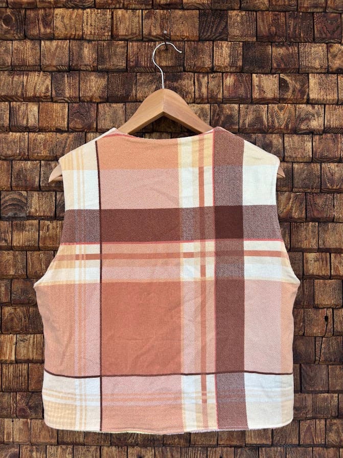 Rückansicht der gewendeten Frottee-Weste 'Honey' von Old Wave. Zeigt das durchgehende, warme Schottenkaro-Design auf der Rückseite vor einer Backsteinwand.