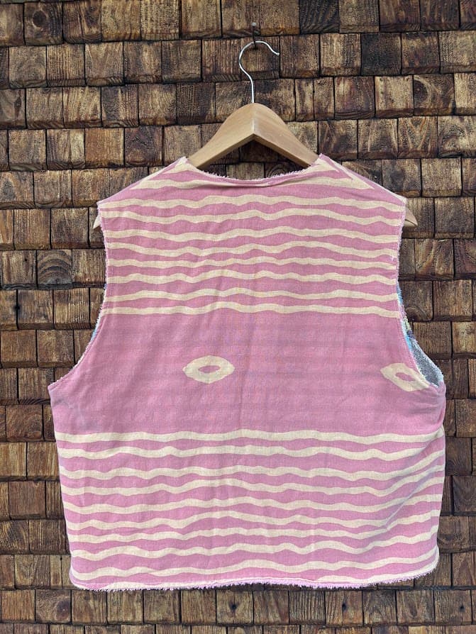 Rückansicht der gewendeten Frottee-Weste 'Sienna' von Old Wave. Zeigt die flächige rosa Rückseite mit feinen gelben Ringelstreifen und einem kleinen Muster-Detail vor einer Backsteinwand.