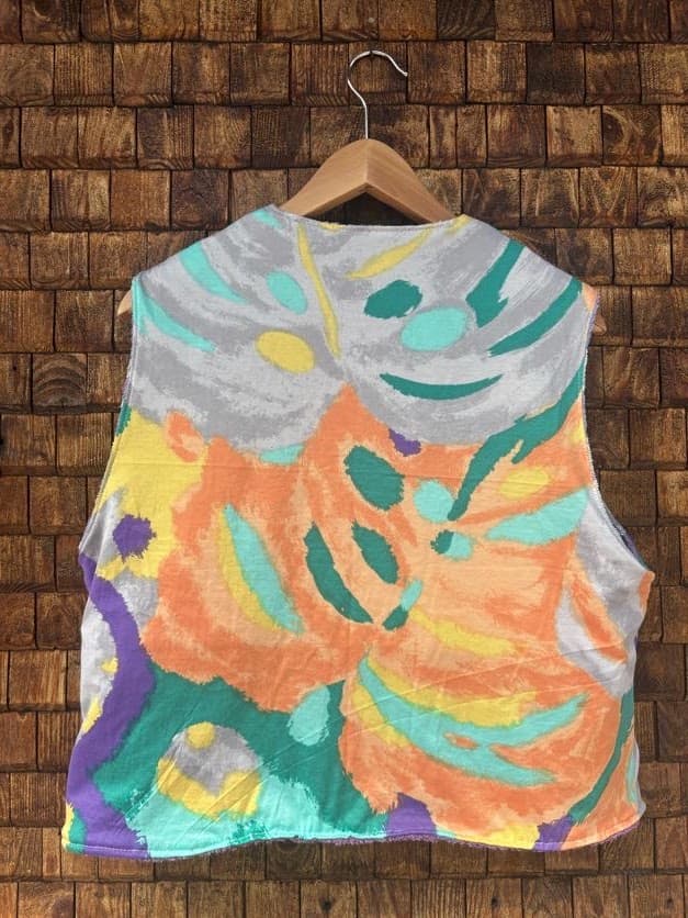 Rückansicht der gewendeten Frottee-Weste 'Violet' von Old Wave. Zeigt die zweigeteilte Rückseite mit fliederfarbenem Ornament-Frottee oben und dunklerem Violett-Akzent am Saum vor einer Backsteinwand.