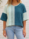 Nahaufnahme eines Models, das das Upcycling-Towel Boxy Shirt „Coconut 73“ von Old Wave trägt. Das kurzärmelige Oversize-Oberteil aus weichem Frotteestoff ist asymmetrisch gestaltet: Die linke Seite (vom Betrachter aus rechts) besteht aus tiefem Petrolblau, während die rechte Seite aus hellbeigem Handtuchstoff gefertigt ist und von einer vertikalen, mintgrün gestreiften Retro-Bordüre geziert wird. Dazu wird eine hellblaue Jeans getragen.