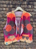 Vorderansicht der gewendeten Frotteeweste 'Blueberry' von Old Wave mit auffälligem 70s-Retro-Blumenmuster in Orange, Magenta und Braun sowie Old Wave Logo-Patch unten links.