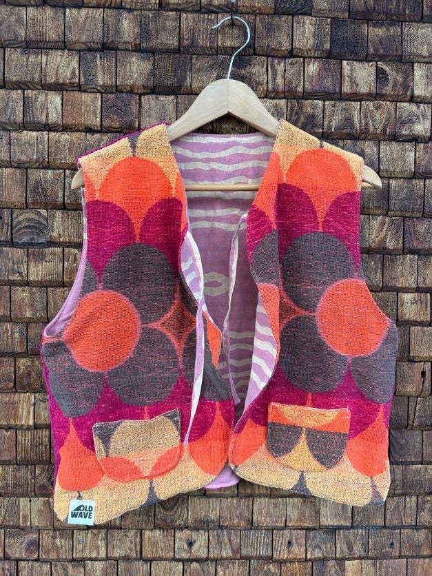 Vorderansicht der gewendeten Frotteeweste 'Blueberry' von Old Wave mit auffälligem 70s-Retro-Blumenmuster in Orange, Magenta und Braun sowie Old Wave Logo-Patch unten links.