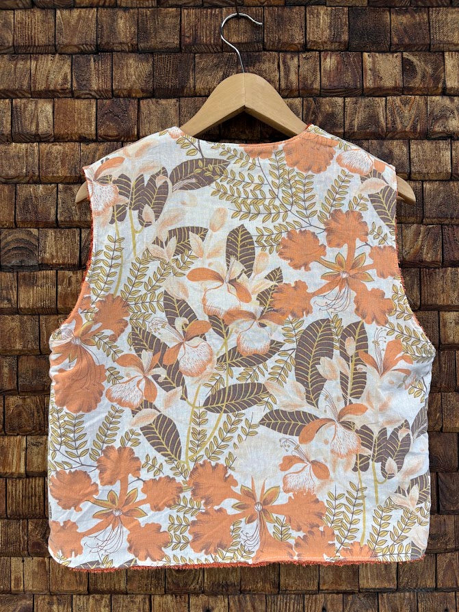Rückansicht der Frottee-Wendeweste 'Laguna' von Old Wave. Zeigt das flächige, botanische Retro-Muster in Erdtönen, Orange und Weiß auf einem Holzkleiderbügel.