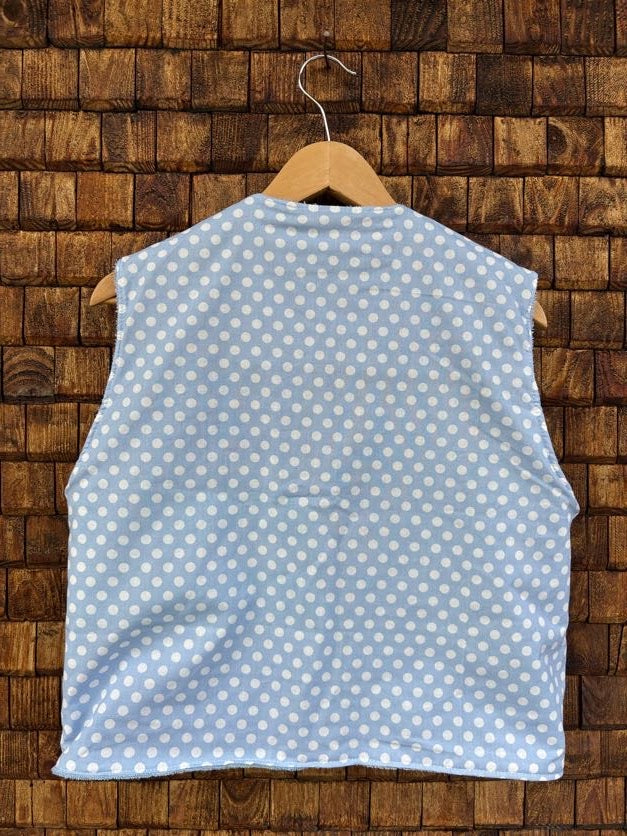Rückansicht der Frottee-Wendeweste 'Ocean' von Old Wave. Zeigt das durchgehende, gleichmäßige Polka-Dot-Muster in Hellblau und Weiß auf einem Holzkleiderbügel.