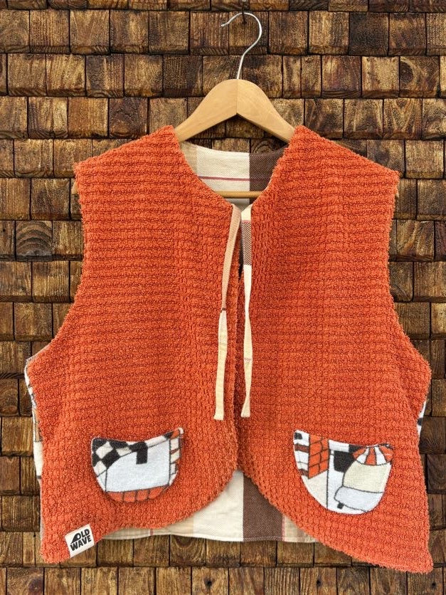 Vorderansicht der gewendeten Frotteeweste 'Papaya' von Old Wave in leuchtendem Terrakotta-Orange mit zwei gemusterten Eingriffstaschen, Bindebändern und Old Wave Logo-Patch unten links.