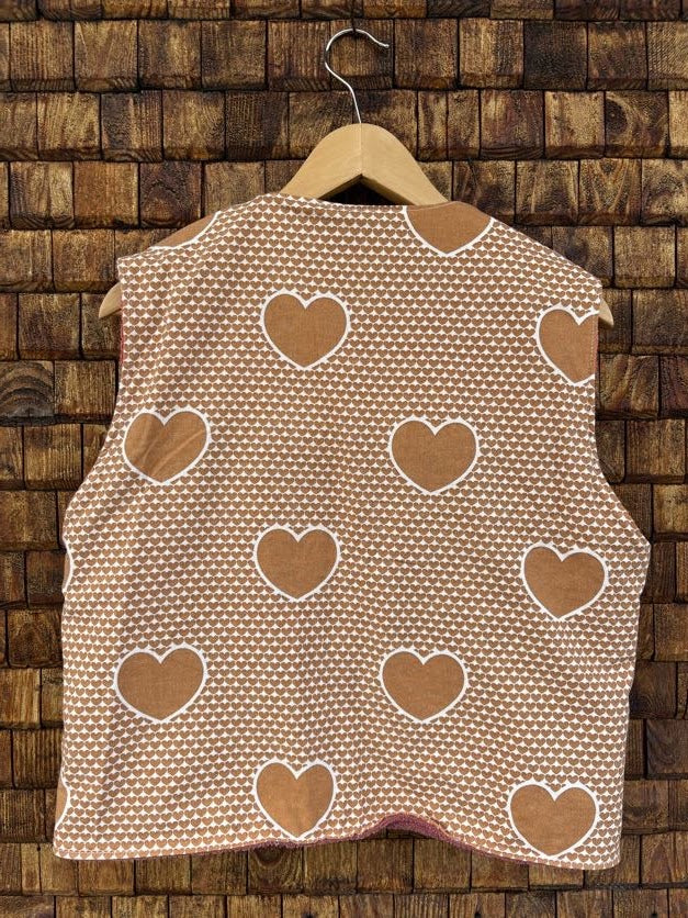 Rückansicht der Frottee-Wendeweste 'Rose-Shell' von Old Wave. Zeigt das gestreifte Frottee-Muster mit verteilt eingenähten Herz-Motiven auf einem Holzkleiderbügel.