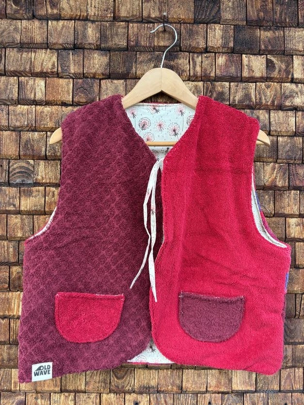 Vorderansicht der gewendeten Weste 'Sol' von Old Wave in kräftigem Magenta und Rot mit zwei aufgesetzten Kontrasttaschen und Bindebändern.
