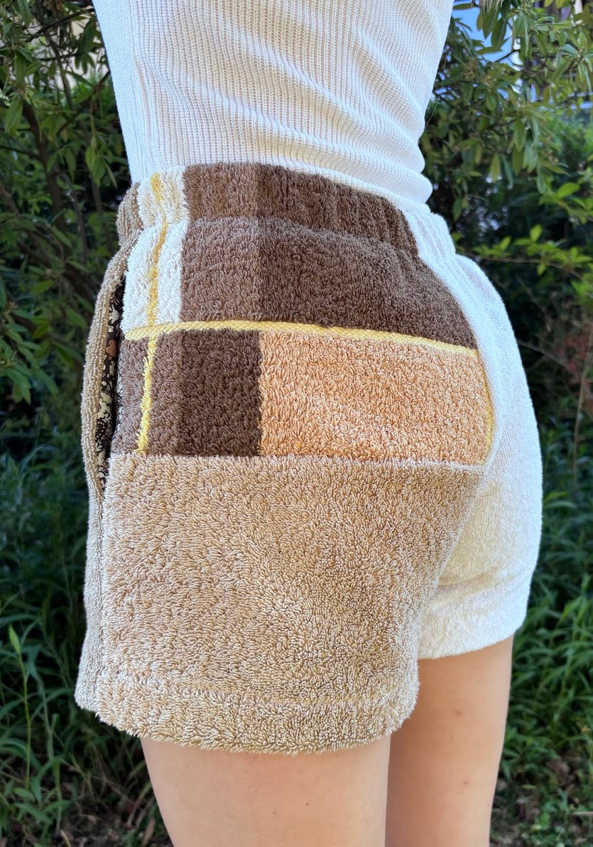 Seitliche Trageansicht der Shorts Meadow Campagna 68 mit Fokus auf das strukturierte Frottee-Patchwork in Braun und Sandtönen sowie die integrierte Seitentasche.