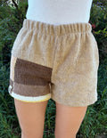 Vorderansicht der am Modell getragenen Frottee-Shorts Meadow Campagna 68 in der Natur. Die bequeme Passform mit elastischem Bund hebt das harmonische Design aus beigen und braunen Vintage-Stoffen hervor.