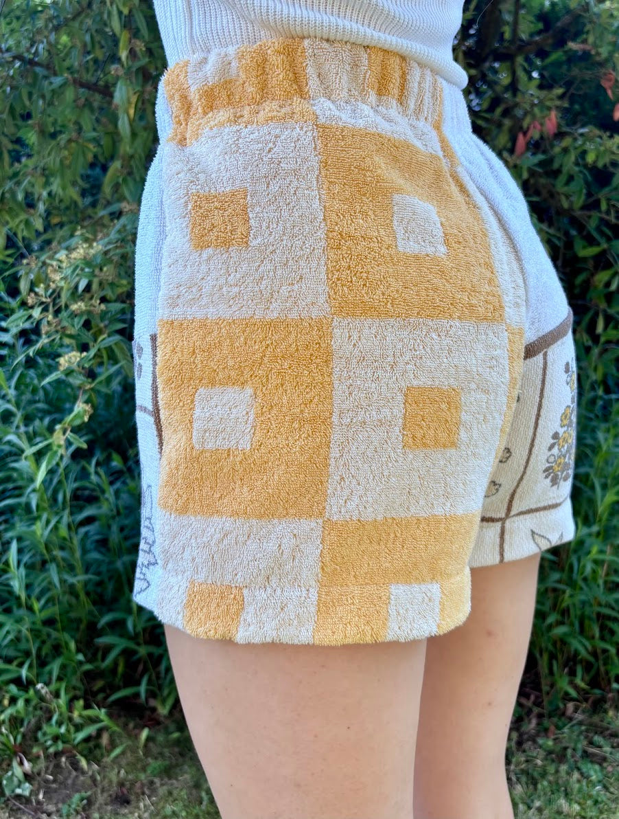 Seitliche Trageansicht von hinten, die das markante gelb-weiße Schachbrettmuster der Upcycling-Shorts Sunfade Twist 71 perfekt in Szene setzt.