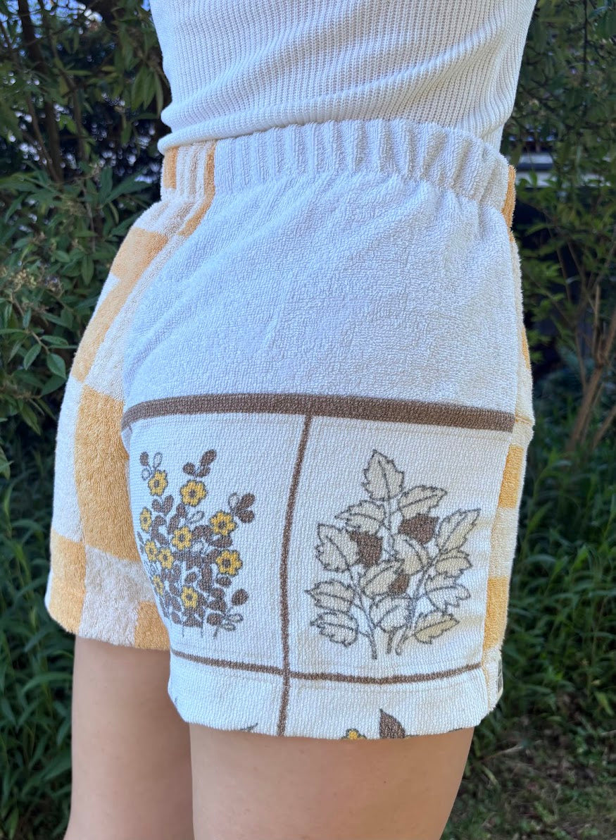 Seitliche Trageansicht von hinten, die das markante gelb-weiße Schachbrettmuster der Upcycling-Shorts Sunfade Twist 71 perfekt in Szene setzt.