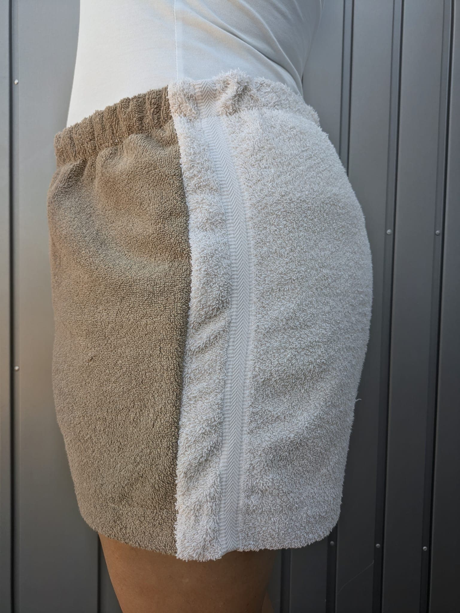 Seitenansicht von rechts der Terra Breeze 79 Shorts. Gezeigt wird das weiße Hosenbein aus dichtem Vintage-Frottee, das an der Seitennaht harmonisch an den sandbraunen Inlay-Stoff grenzt.